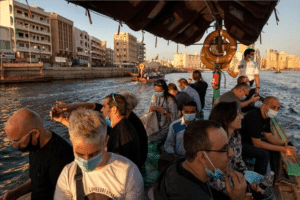 As the sun sets, casting a warm glow, a group on a boat travels along a city canal. Some are taking photos or looking at the water. Amidst masked conversations and laughter, you could easily be falling in love with this moment that feels as vibrant as Dubais skyline.